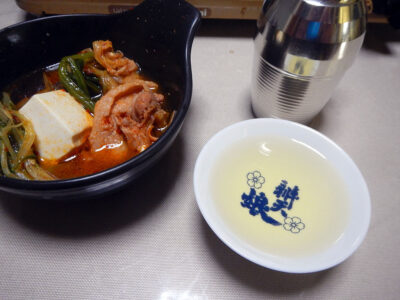 旭若松・雄町の熱燗で大根の醬油漬けや自家製キムチを使った豚肉のチゲ鍋をいただく